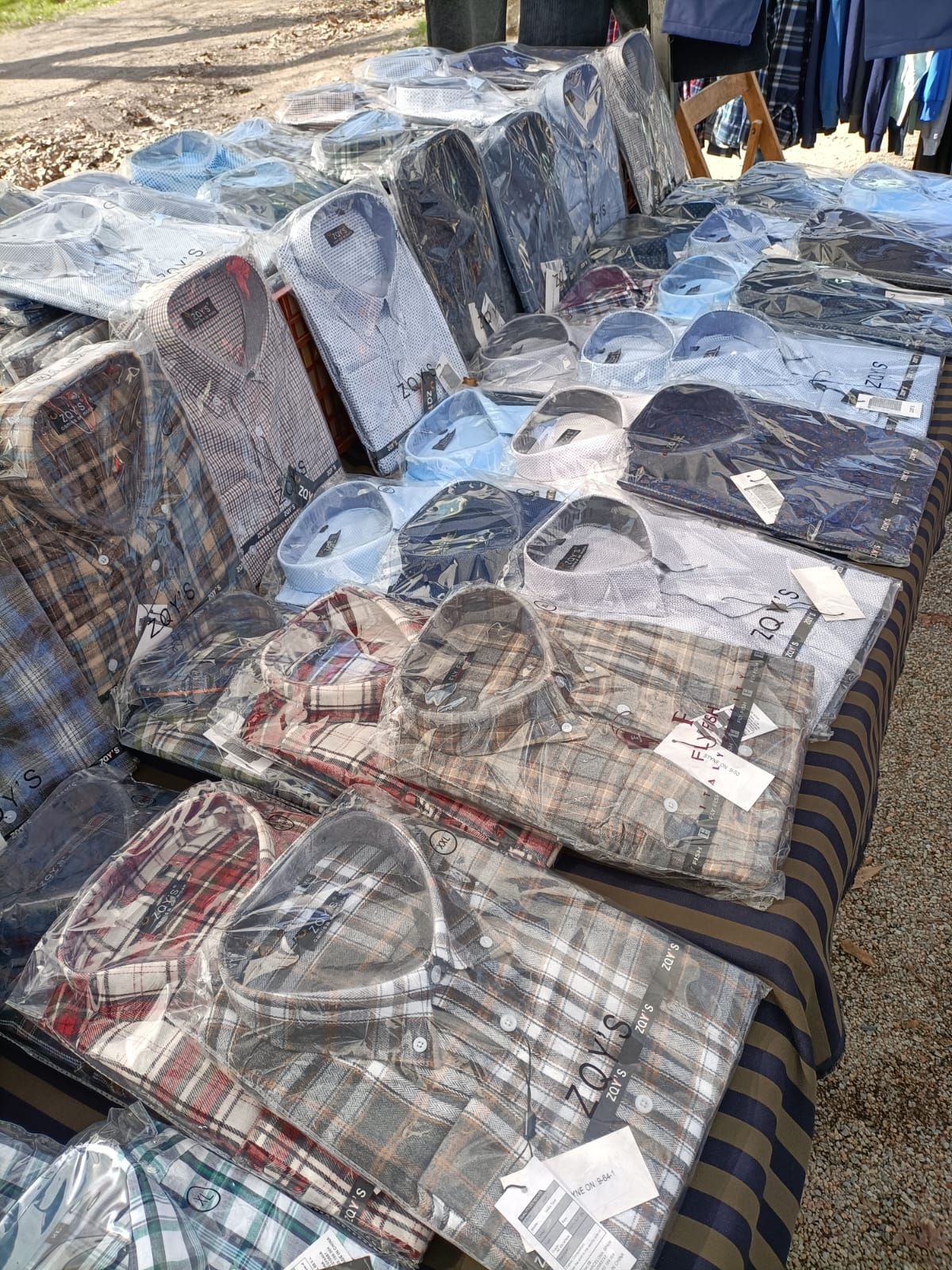 Dos camisas blancas, un reloj y gafas de sol están sobre una mesa blanca.