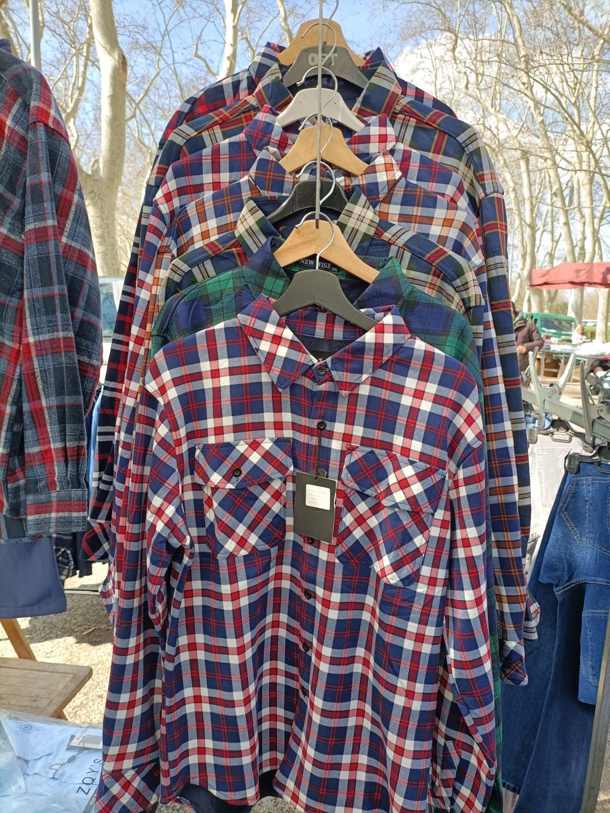 Hay cuatro camisas colgadas en una percha en una pared.