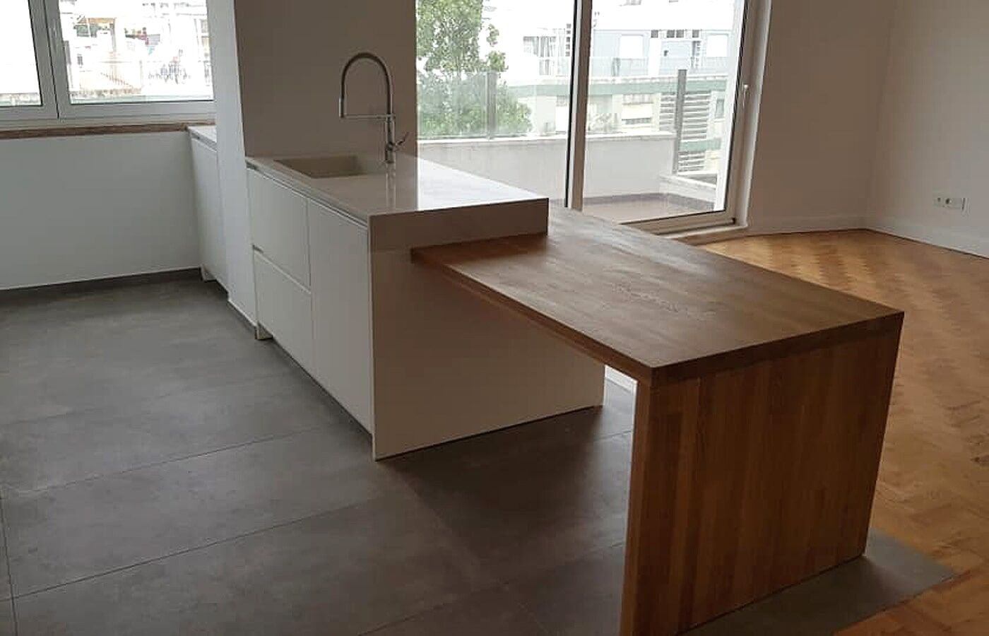 Ilha de cozinha moderna com armários brancos, bancada de madeira e pia embutida.