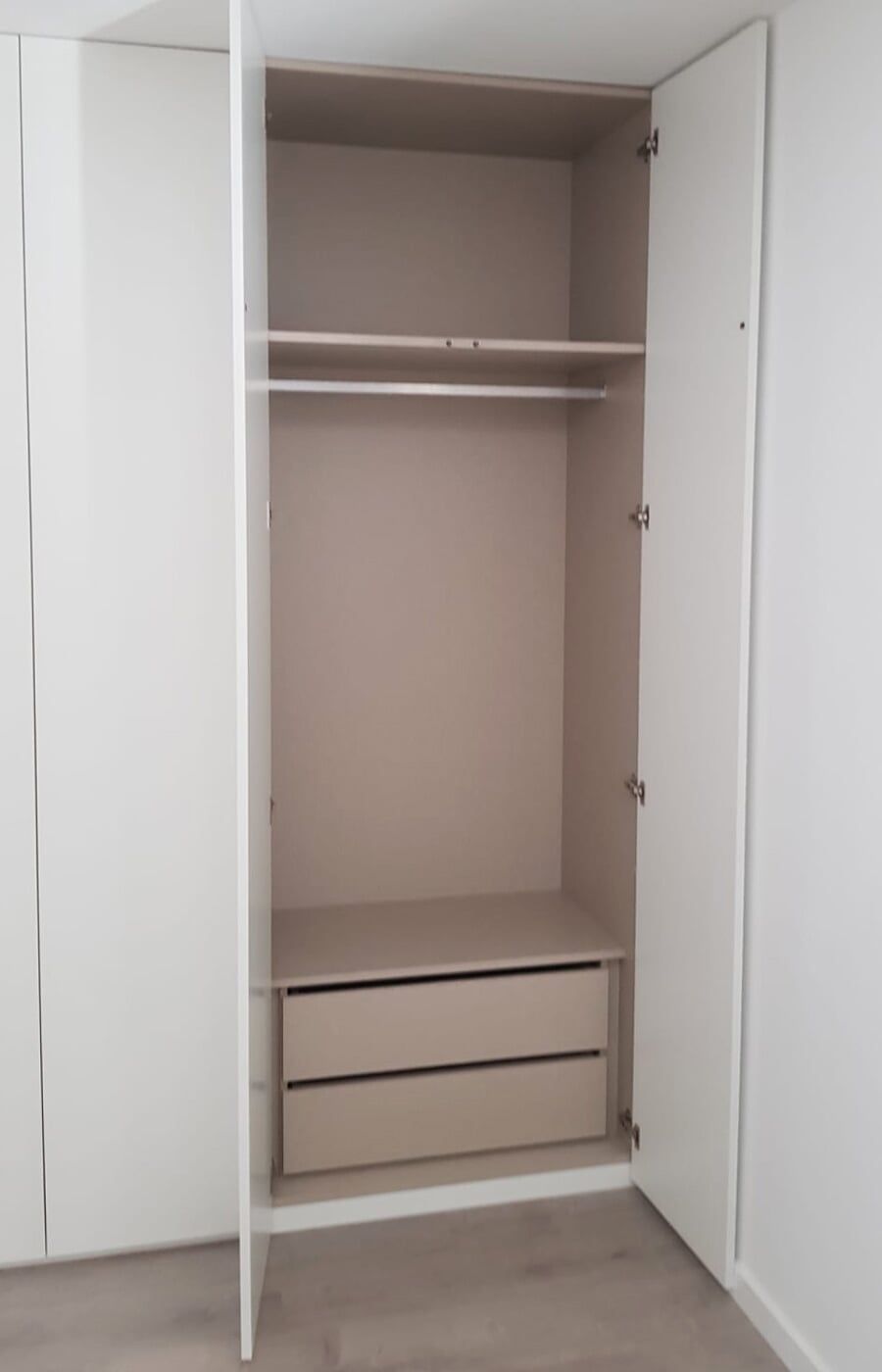 Guarda-roupa branco com portas abertas e interior bege. Inclui um varão para roupas e duas gavetas.