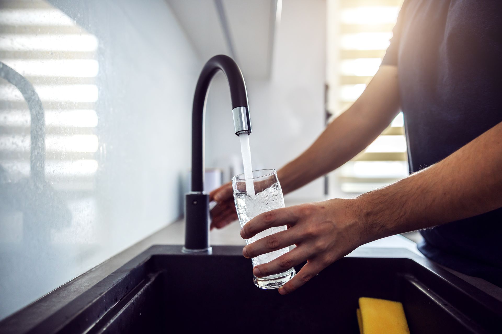 Homme se servant un verre d'eau au robinet