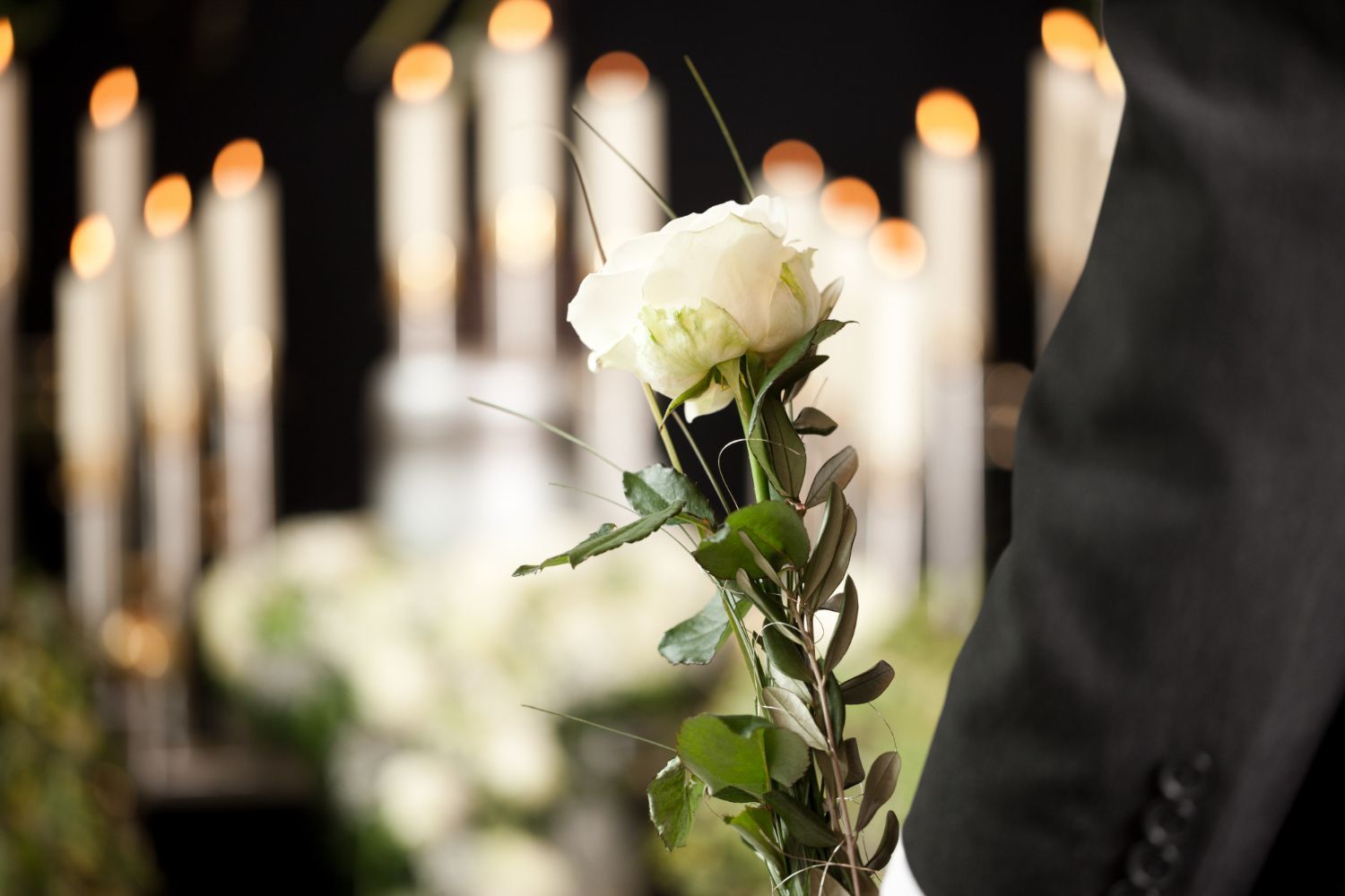 Arranjo floral para casamento com velas, grama seca e rosas cor de pêssego em um ambiente verde escuro.