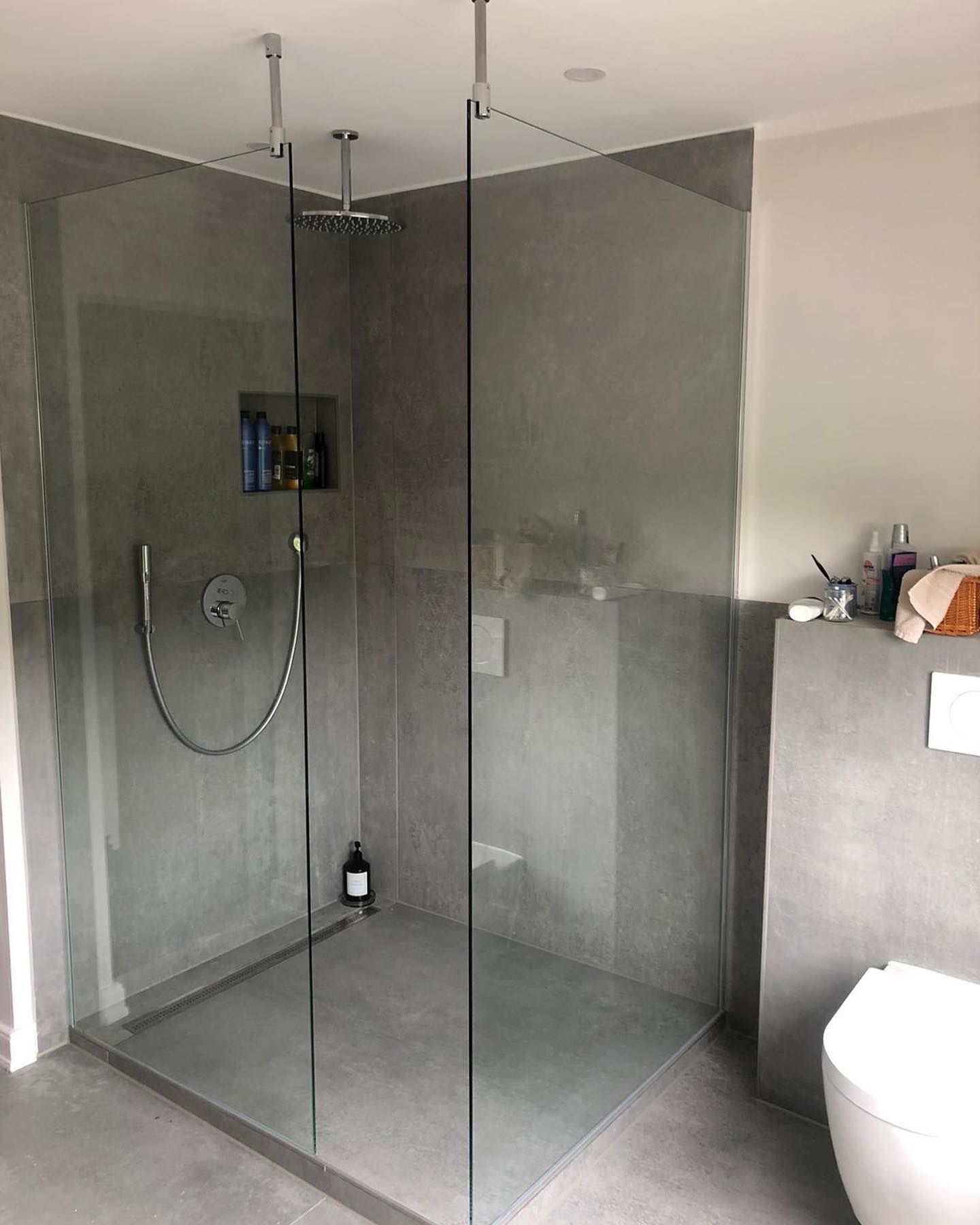 Ein Badezimmer mit ebenerdiger Dusche und Toilette.