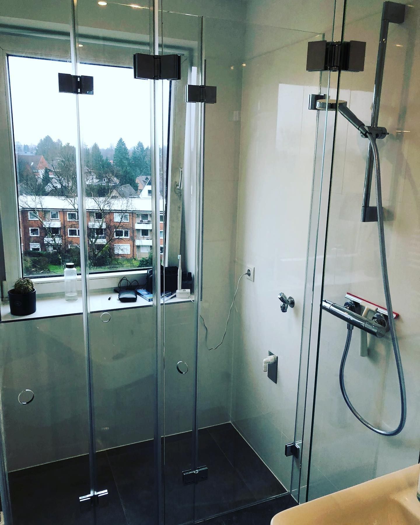 Ein Badezimmer mit ebenerdiger Dusche und Fenster