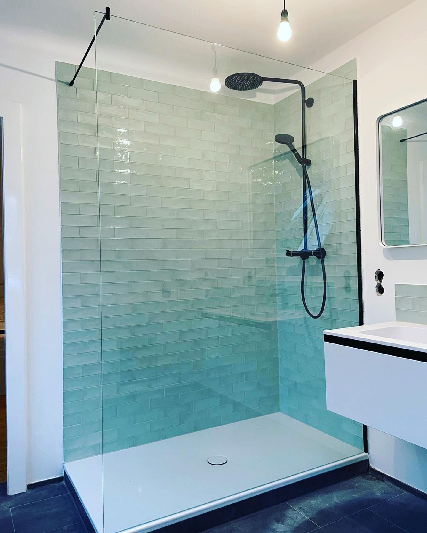 Ein Badezimmer mit ebenerdiger Dusche und Waschbecken.