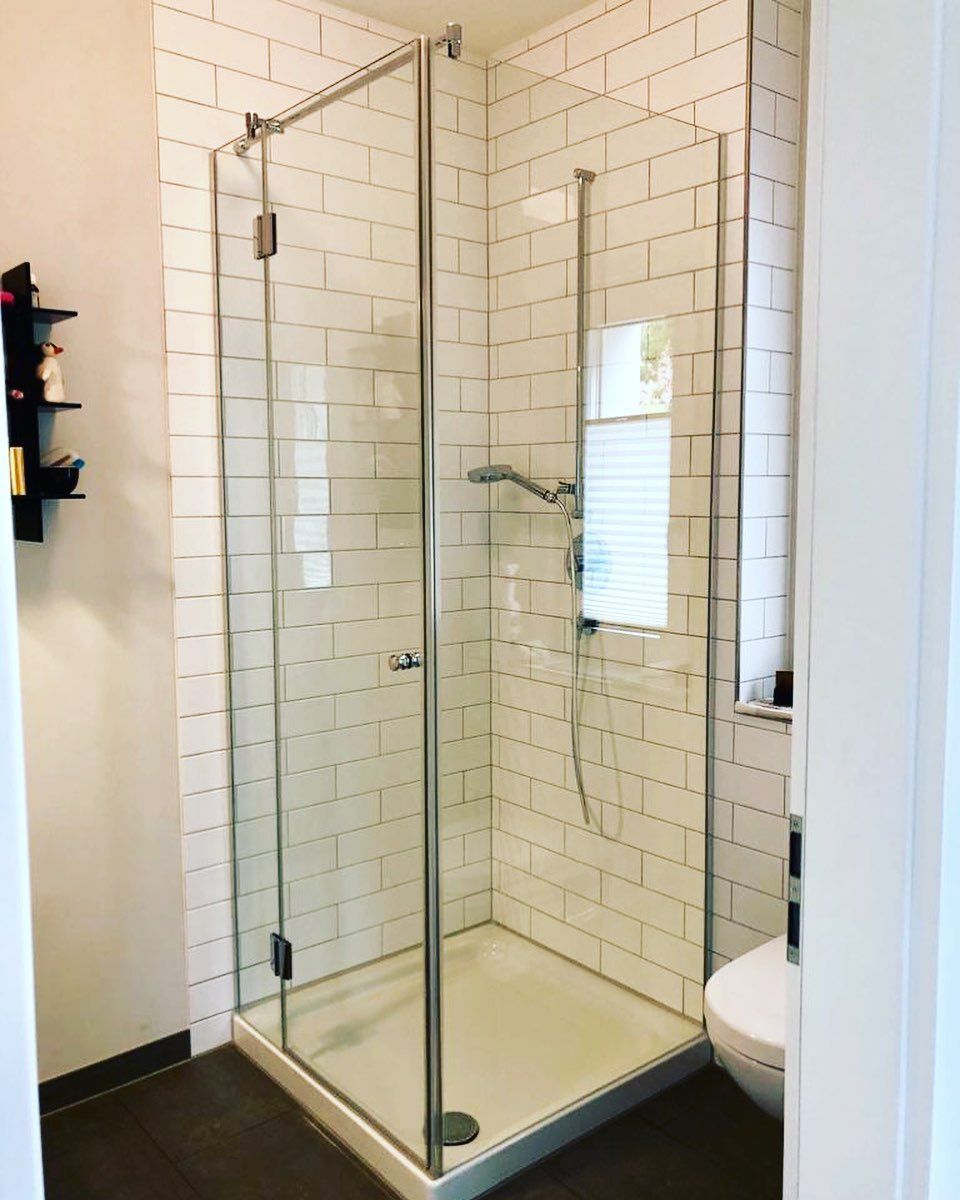 Ein Badezimmer mit weißen Fliesen und einer ebenerdigen Dusche