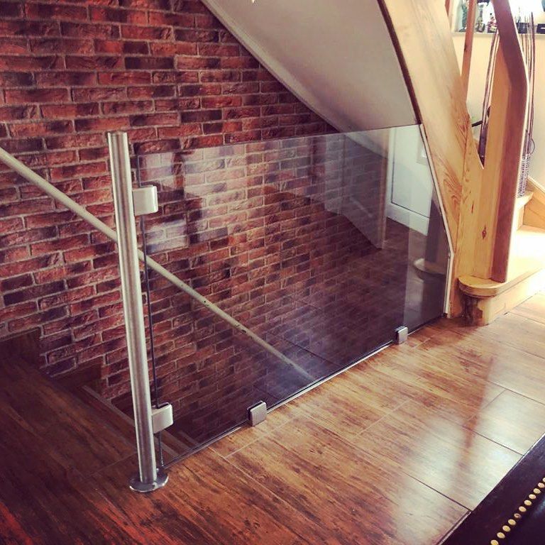 Eine Treppe mit einem Glasgeländer und einer Ziegelwand