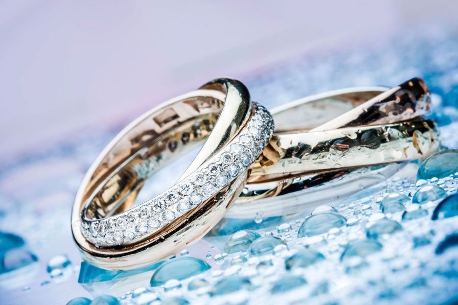 Un primer plano de dos anillos de boda sobre una superficie azul.