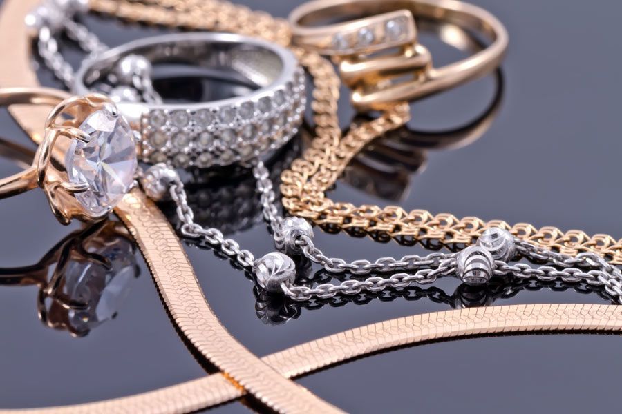 Una pila de joyas de oro y plata sobre una superficie negra