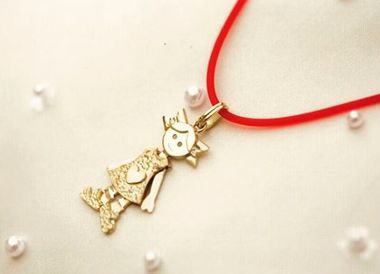 Un collar con un colgante de oro en un cordón rojo.