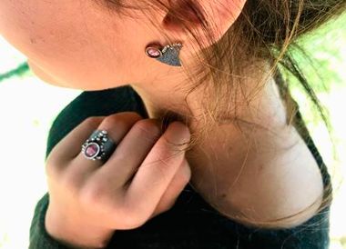 Un primer plano de una mujer que lleva pendientes y un anillo.