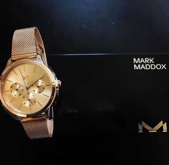Un reloj de oro se encuentra encima de una caja negra que dice Mark Maddox.