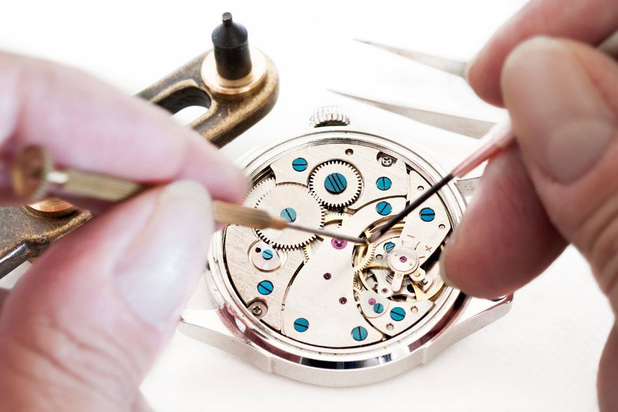 Una persona está arreglando un reloj con pinzas y un cepillo.