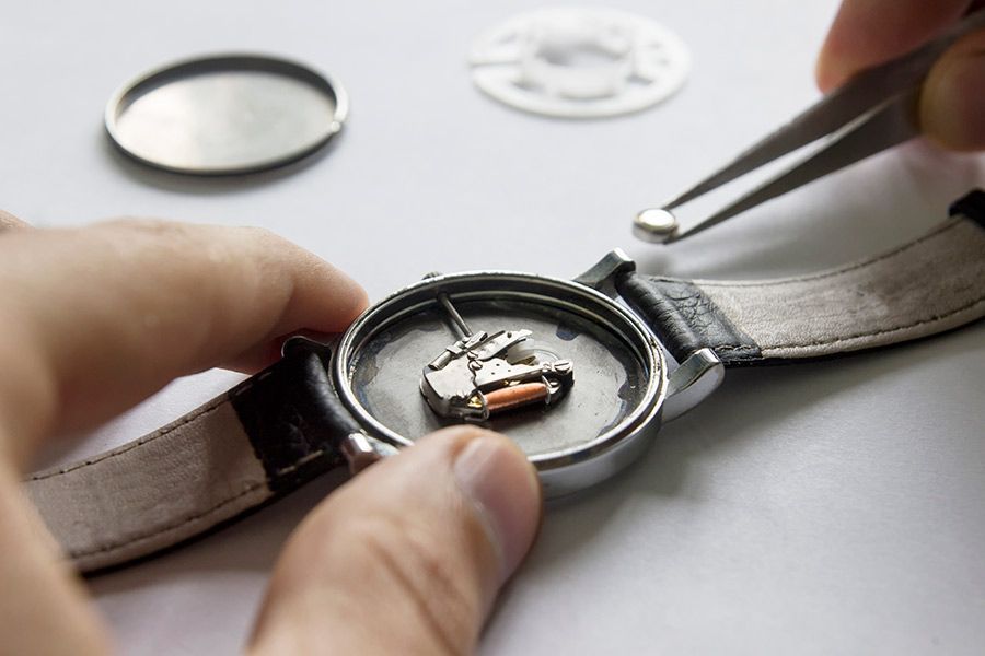 Una persona está arreglando un reloj con pinzas.