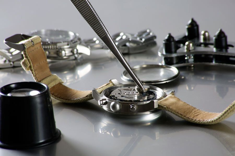 Se está reparando un reloj con un par de pinzas.