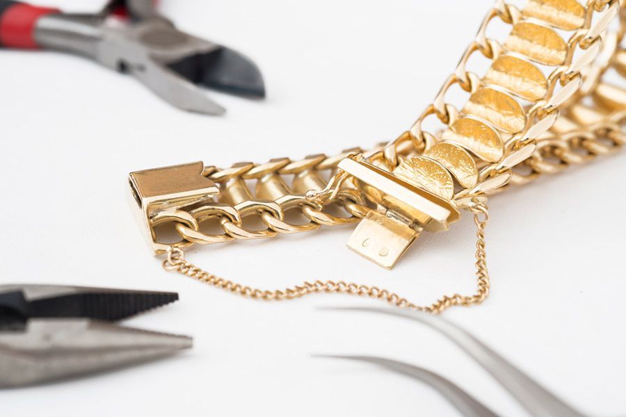 Se está reparando una pulsera de oro con alicates y tijeras.