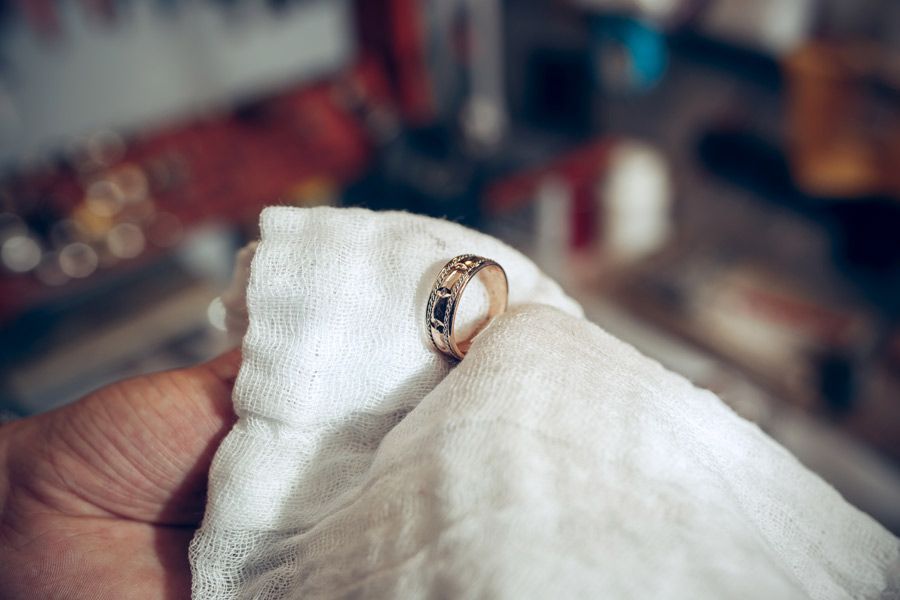 Una persona está limpiando un anillo de oro con un paño.