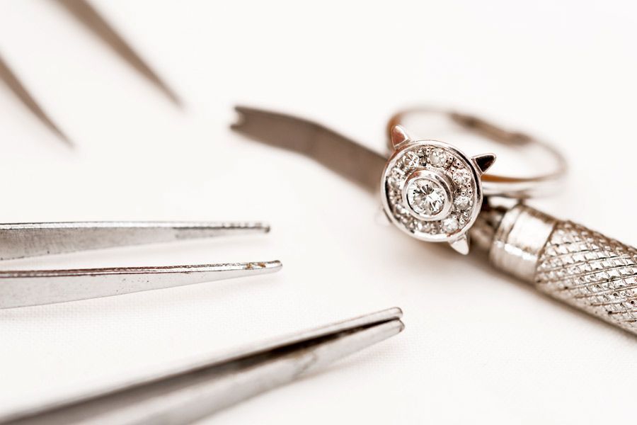 Se está reparando un anillo de diamantes con un par de pinzas.