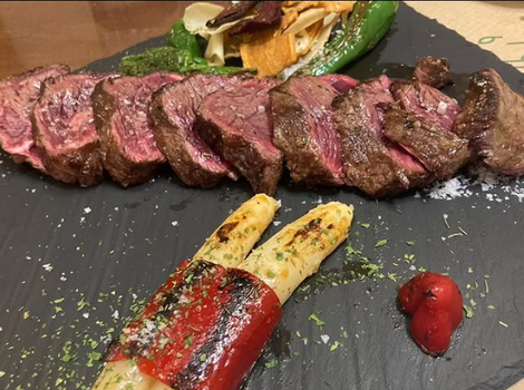 Filete de ternera cortado a la parrilla con pimientos y verduras a la parrilla sobre pizarra negra.