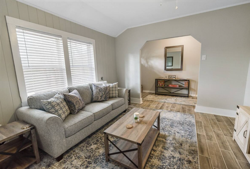 A living room with a couch , coffee table , and mirror.