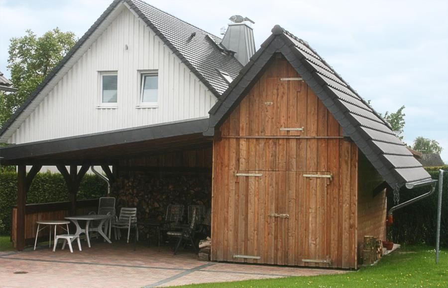 Ein weißes Haus mit einer Holzgarage darunter