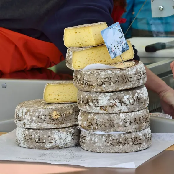 Pile de fromages ronds à croûte grise et à pâte jaune pâle, avec une étiquette de prix dessus.
