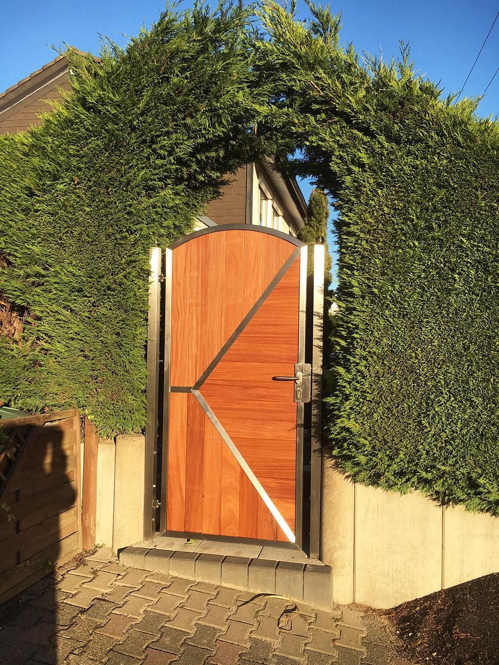 Ein Holztor ist von einer üppigen grünen Hecke umgeben