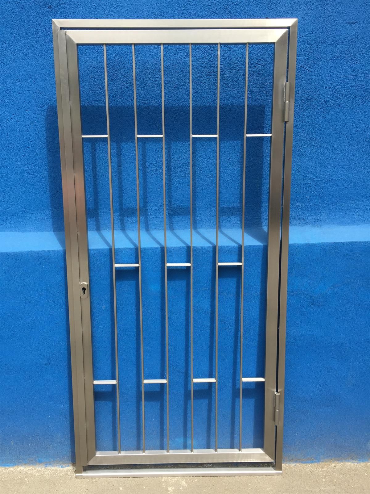 Ein Edelstahltor steht vor einer blauen Wand