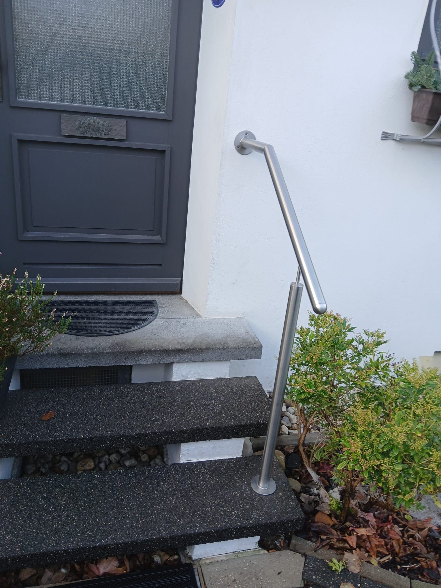 Eine Treppe, die zu einer Tür mit einem Geländer aus Edelstahl führt.