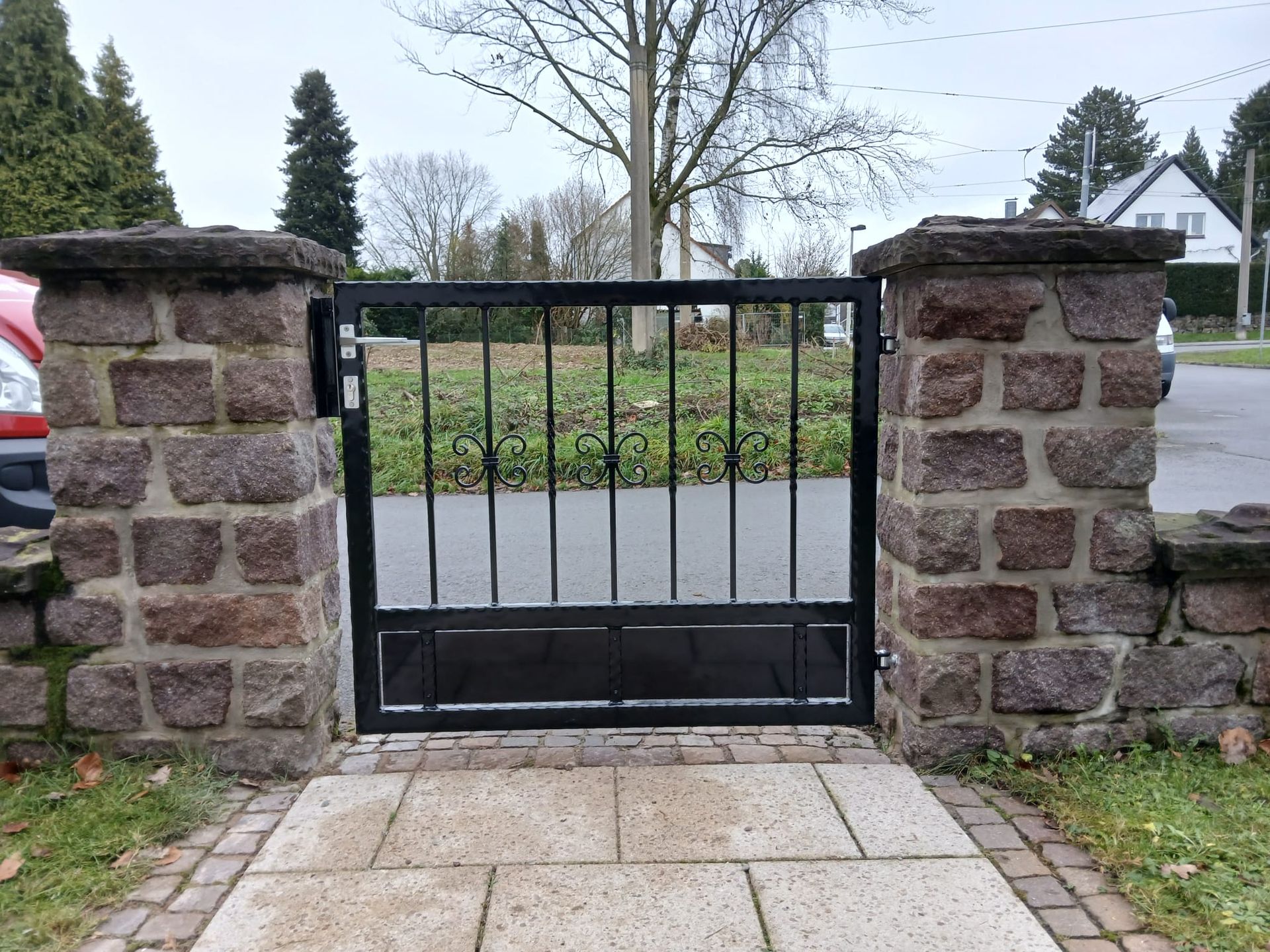 Eine Backsteinmauer mit einem schwarzen Tor davor