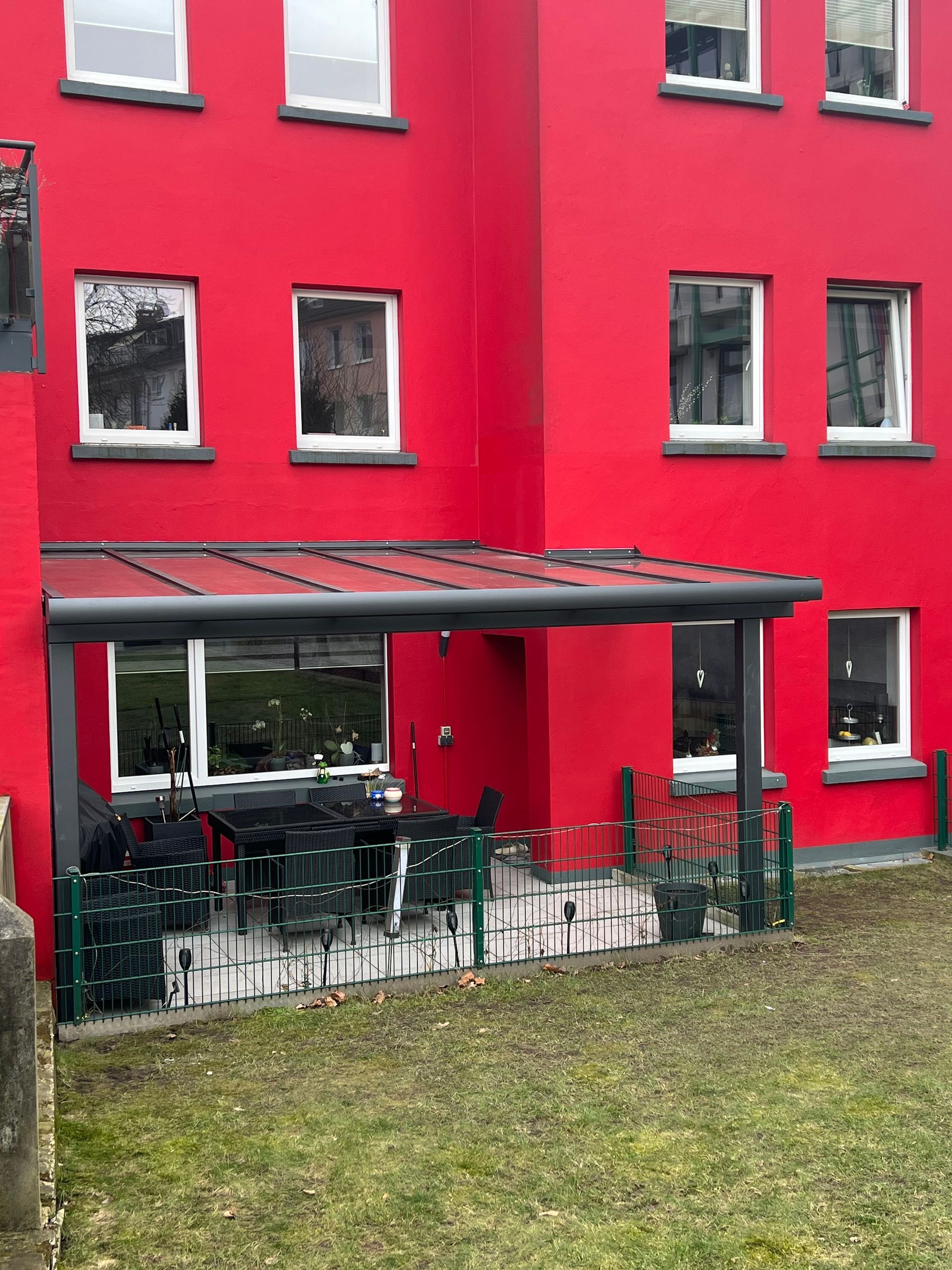 Ein großes rotes Gebäude mit einer Terrasse und einer Terrassen-Überdachung davor