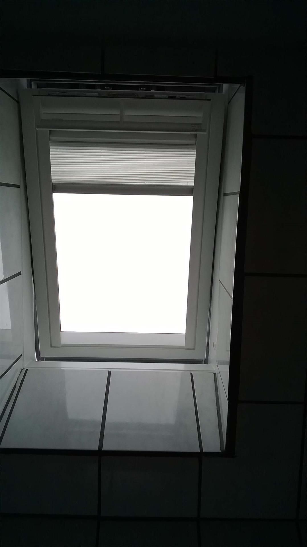 Ein Fenster in einem Badezimmer mit einer Jalousie daran.