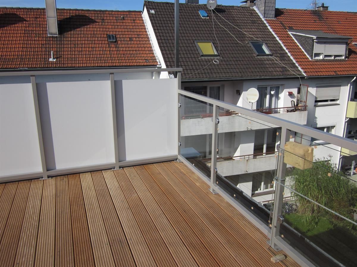 Ein Balkon mit Edelstahlgeländer und Holzterrasse