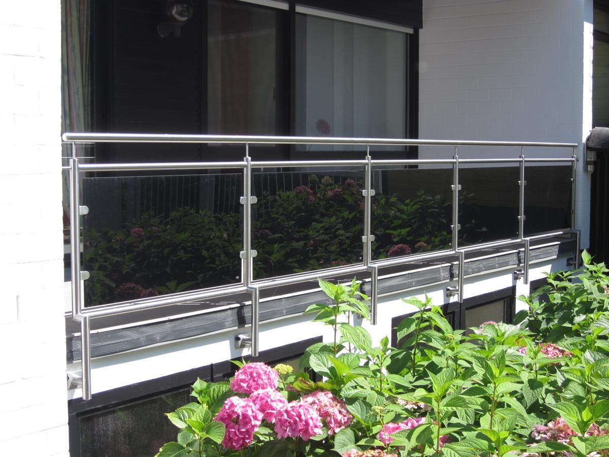 Ein Balkon mit Edelstahlgeländer und Blumen davor