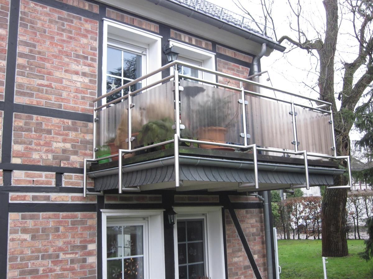 Ein Backsteingebäude mit einem Balkon mit klarem Glas