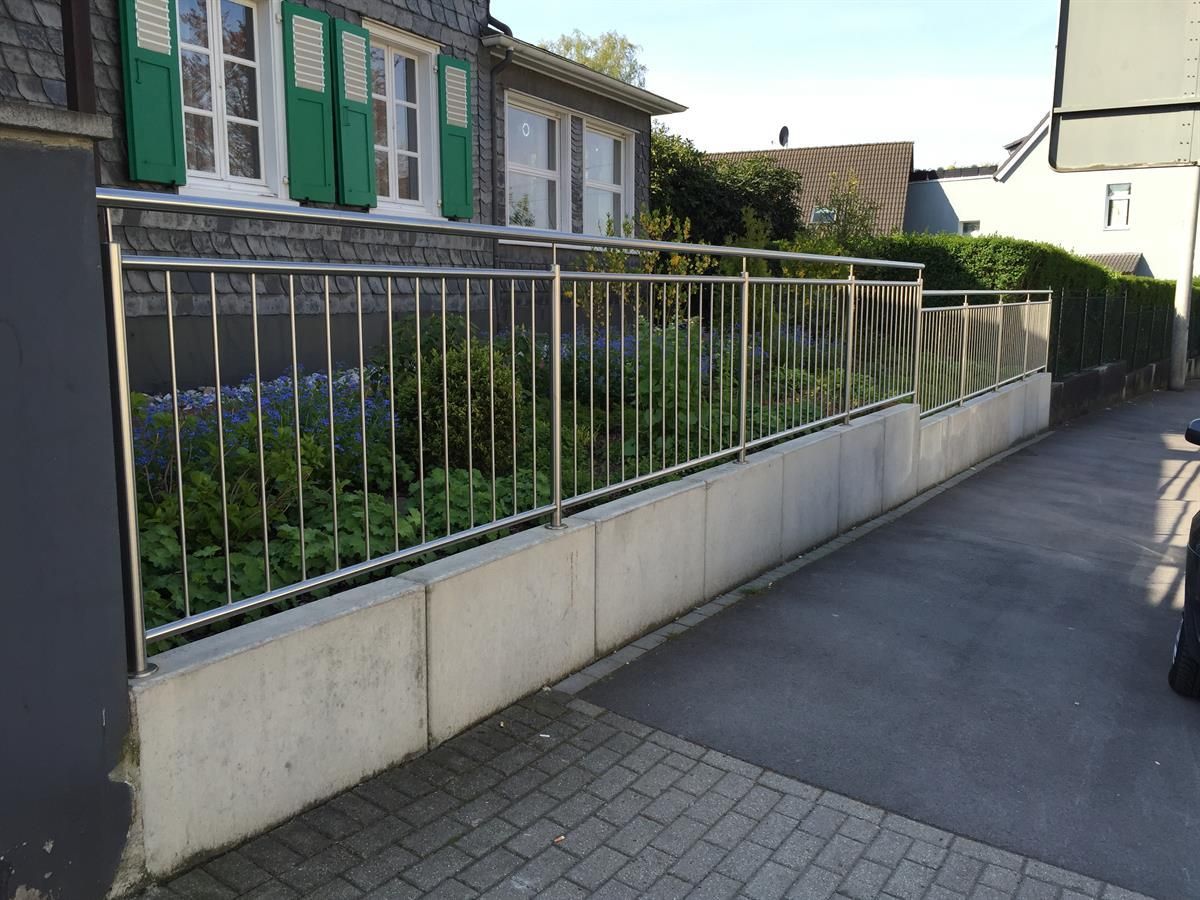 Ein Edelstahlzaun mit grünen Fensterläden