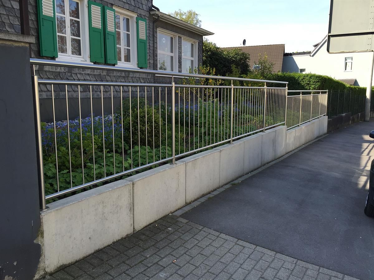 Ein Edelstahlzaun mit grünen Fensterläden
