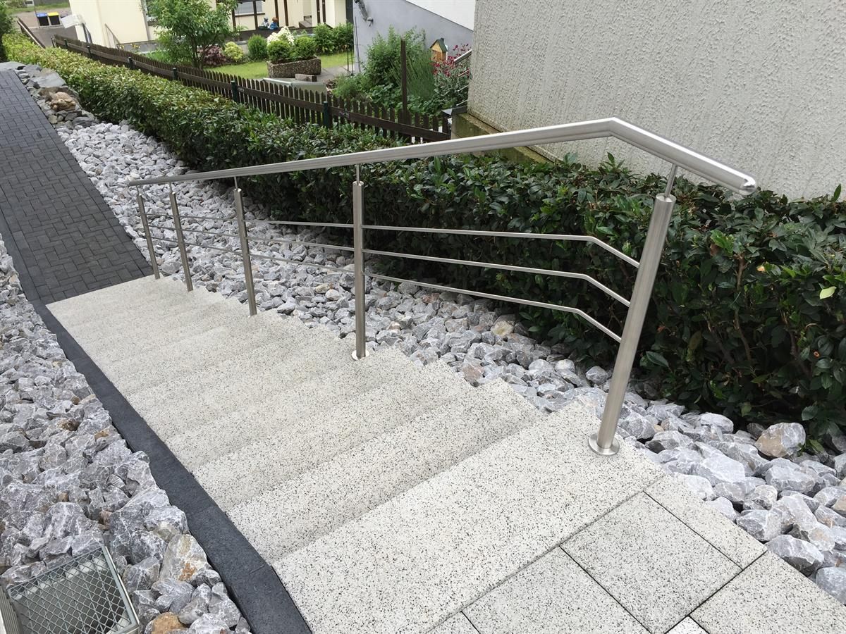 Eine Treppe, die zu einem Haus mit einem Edelstahlgeländer hinaufführt.