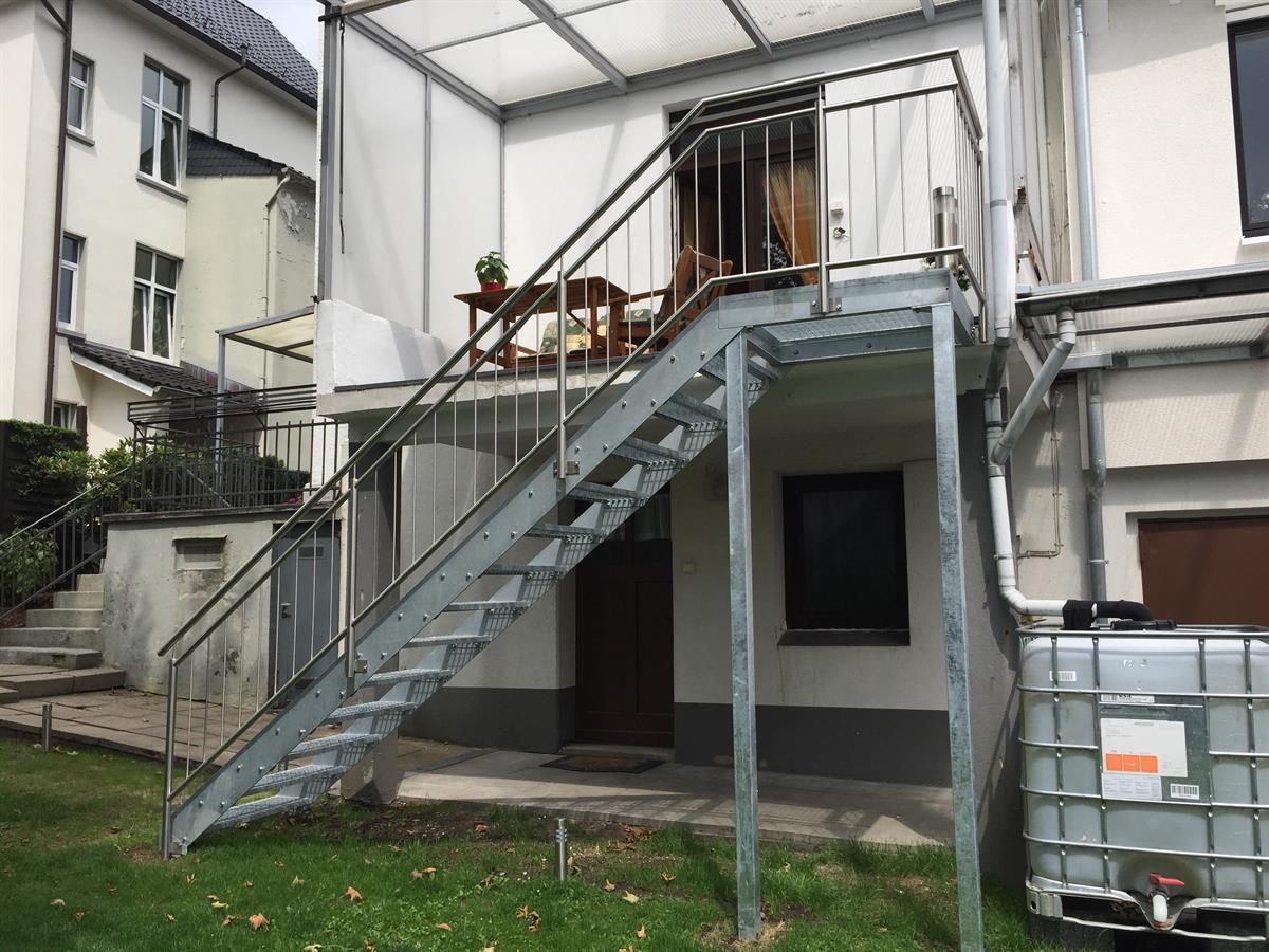 Eine Metalltreppe, die zu einem Balkon an der Seite eines Hauses führt