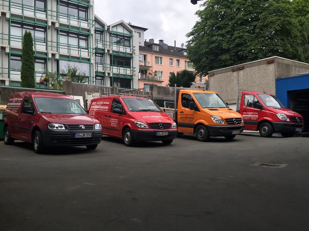 Eine Reihe roter und orangefarbener Lieferwagen steht auf einem Parkplatz