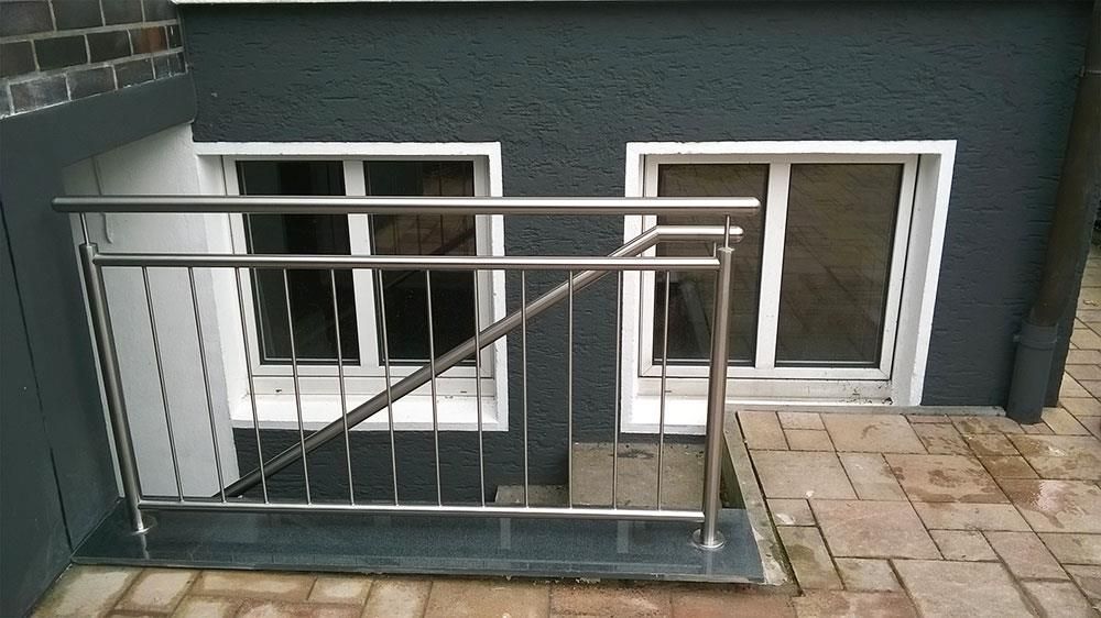 Eine Treppe, die zu einem Fenster mit einem Edelstahlgeländer führt