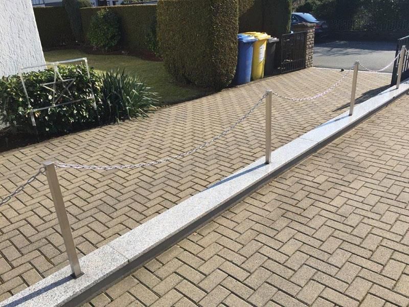 Eine gemauerte Auffahrt mit einem Maschendrahtzaun vor einem Haus