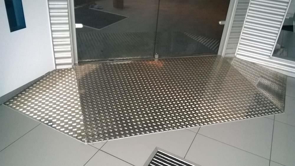 Eine Edelstahlmatte liegt auf dem Boden vor einer Glastür