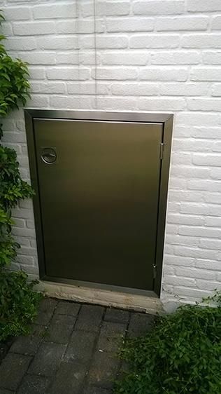 In eine weiße Ziegelwand ist eine Edelstahltür eingebaut.