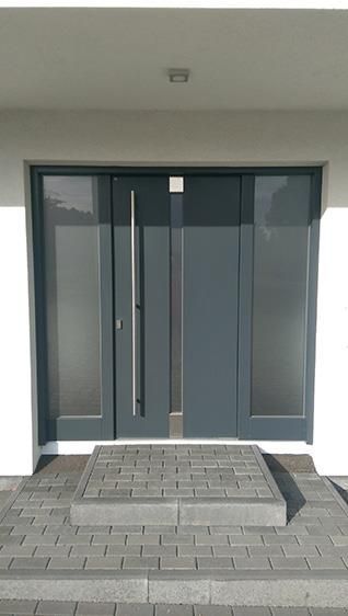 Die Eingangstür eines Hauses, zu der ein gemauerter Weg führt.