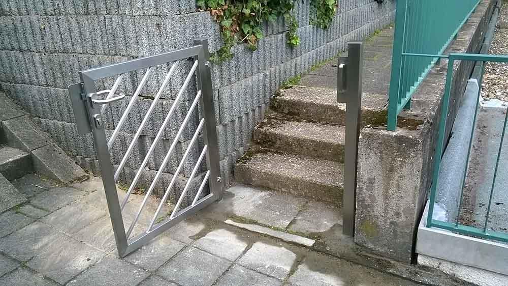 Durch ein Metalltor gelangt man zu einer Treppe.
