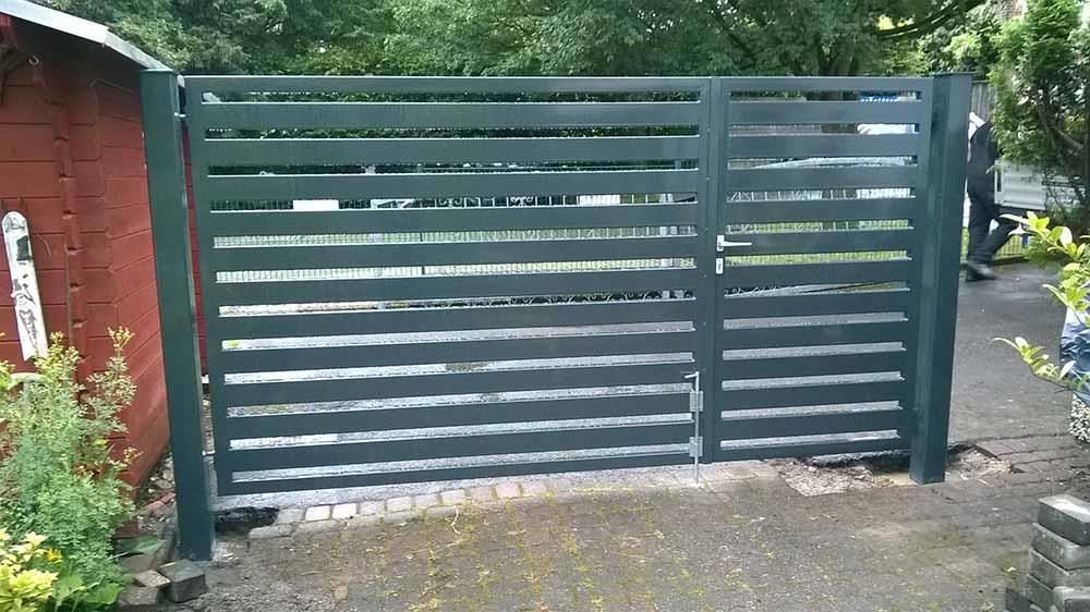 Ein schwarzer Zaun mit einem roten Schuppen im Hintergrund