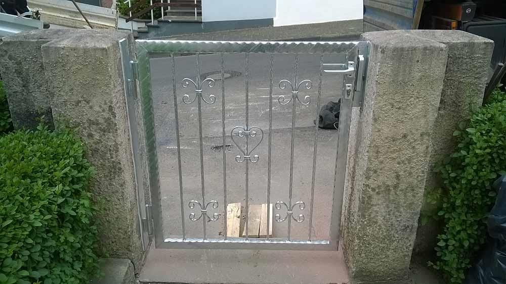 Vor einer Betonmauer steht ein Metalltor.