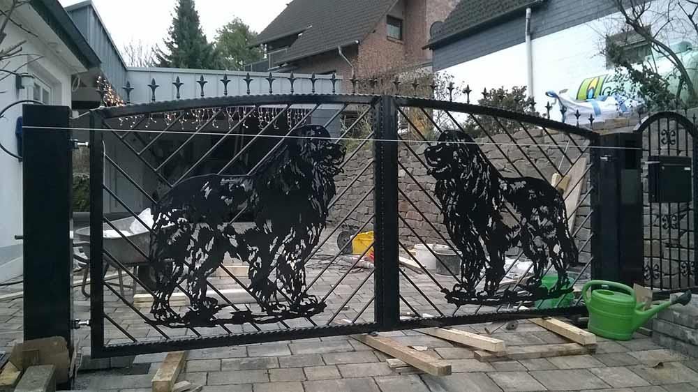 Vor einem Haus steht ein schwarzes Tor mit zwei Löwen darauf.