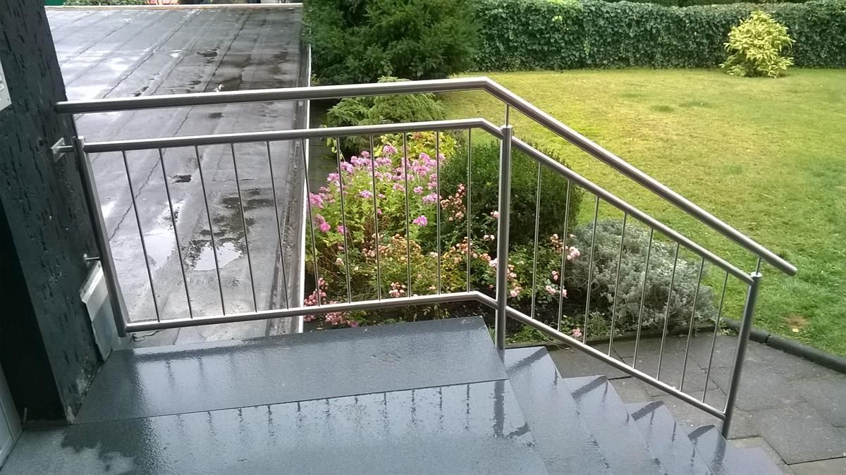 Eine Treppe mit Edelstahlgeländer und Blumen im Hintergrund